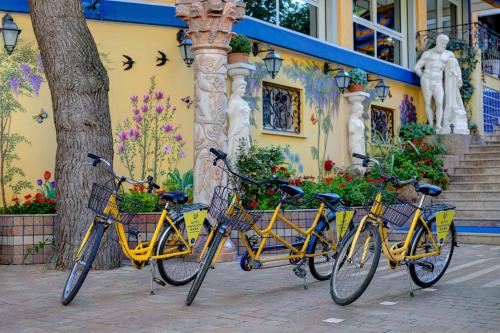 three bikes parked in front of a building with flowers at Hotel Napoleon in Lido di Jesolo