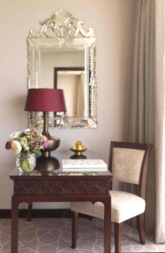 a desk with a lamp and a mirror and a chair at Bab Al Qasr Residence in Abu Dhabi