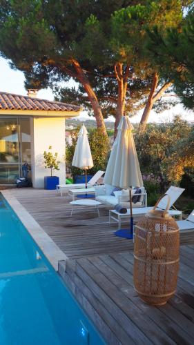 uma piscina com cadeiras e guarda-sóis ao lado de uma casa em Les Suites d'Agosta em Porticcio