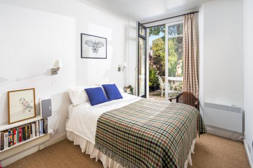 a bedroom with a bed with blue pillows and a window at ALTIDO Sunny 1-bed flat with terrace in Bayswater, near Paddington in London