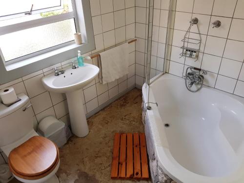a bathroom with a sink and a tub and a toilet at Beachcombers in Agulhas