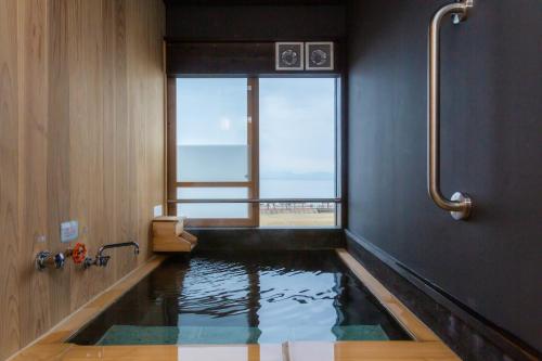 a bath room with a pool of water in a bathroom at Iseya, Seaview Private Onsen Bath in Unzen