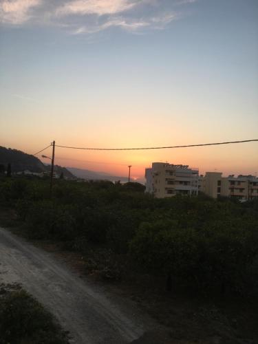 a dirt road with the sunset in the background at Lovely Apartment Next to the Sea Lygia Korinthias in Liyiá