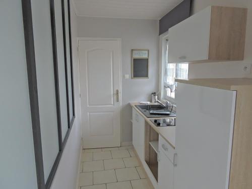 uma cozinha branca com um lavatório e uma porta em la linoterie em Colembert