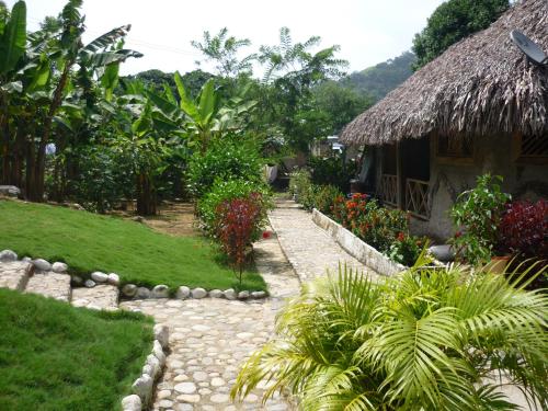 a stone path leading to a house with a grass roof at Posadas Ecoturisticas Seineken in El Zaino