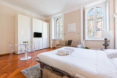 um quarto com uma grande cama branca e uma mesa em Porta Romana Cozy Studio em Milão