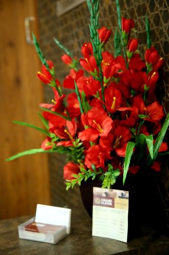 a vase of red flowers sitting on a table at Grand Oliver in Chennai