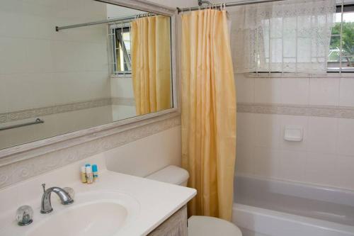 ein Badezimmer mit einem Waschbecken, einem WC und einem Spiegel in der Unterkunft Vida Mejor - Poolside in Saint James