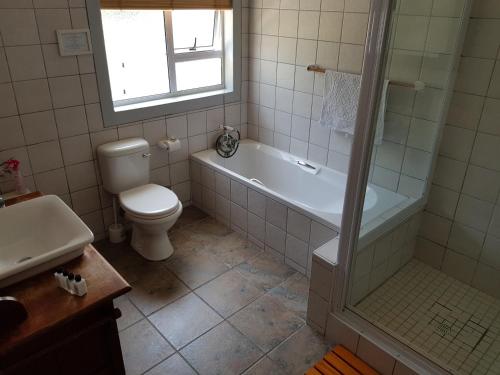 a bathroom with a tub and a toilet and a sink at Beachcombers in Agulhas
