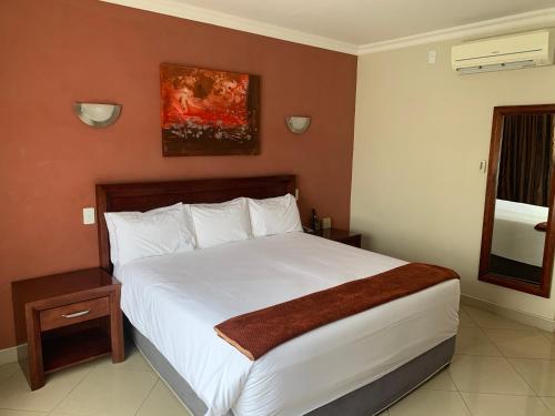 a bedroom with a large white bed and a window at Royal Hotel in Polokwane