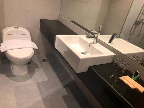een badkamer met een wit toilet en een wastafel bij Mahkota Hotel Singkawang in Singkawang
