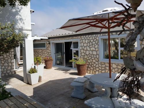 a patio with a table and an umbrella at Beachcombers in Agulhas