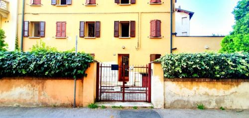 un edificio giallo con un cancello rosso davanti di GUEST HOUSE MONTEGRAPPA a Reggio Emilia