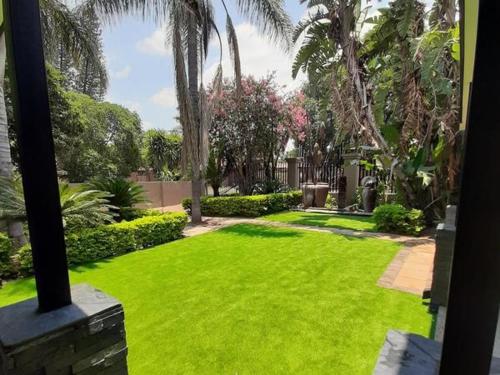 a yard with green grass and palm trees at Copperwood Hotel and Conferencing in Brits