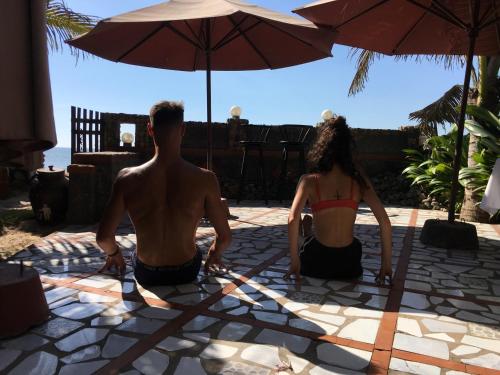 a man and a woman sitting under an umbrella at Sầm Sơn Boutique Hotel Phan Thiết in Phan Thiet