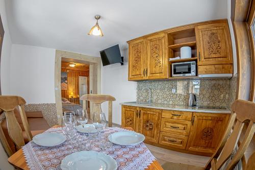 a kitchen with a table with plates and glasses on it at Apartamenty i pokoje Pod Limbami - sauna, tężnia in Bukowina Tatrzańska