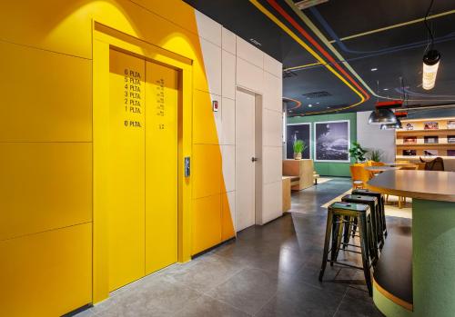a yellow wall in a restaurant with a table and stool at B&B HOTEL Castellón in Castellón de la Plana