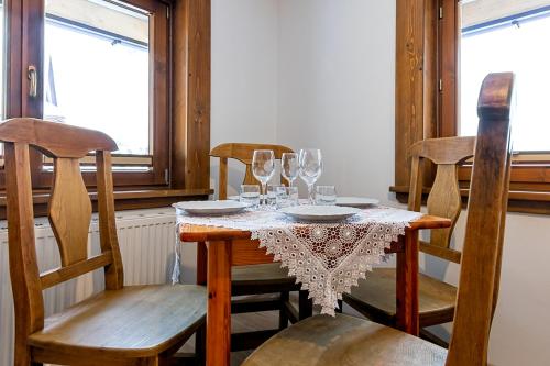 a dining room table with chairs and wine glasses at Apartamenty i pokoje Pod Limbami - sauna, tężnia in Bukowina Tatrzańska