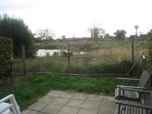 a view of a pond with two chairs and a bird feeder at Condor 19 in Nieuwpoort