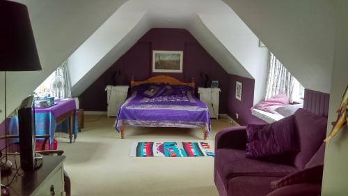 Orchard Pond Bed & Breakfast في دوكسفورد: غرفة نوم مع سرير أرجواني في العلية