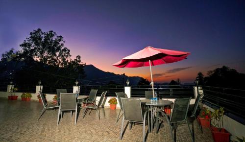 a patio with a table and chairs and an umbrella at Mayur Hotel Bar And Restaurant in Solan