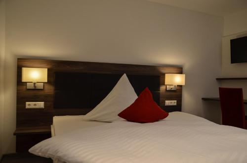 a bedroom with a white bed with a red pillow at Hotel Restaurant Lamm in Mönsheim