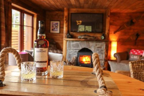 een fles whisky op een houten tafel met glazen bij Snowy River Lodge in Aviemore