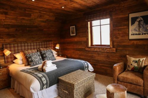 a bedroom with wooden walls and a bed and a chair at Snowy River Lodge in Aviemore