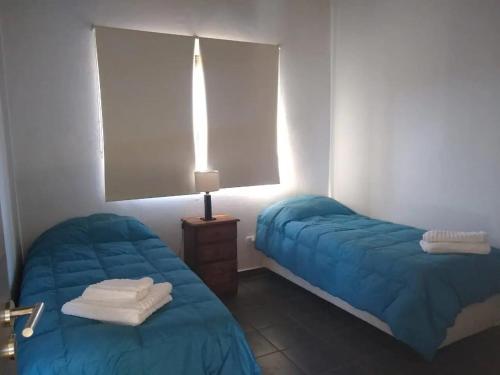una habitación de hotel con 2 camas y una lámpara en Cabañas Otium en Uspallata