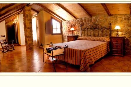 una camera con un grande letto e un muro di pietra di VILLA LOS MELLIZOS a Ronda