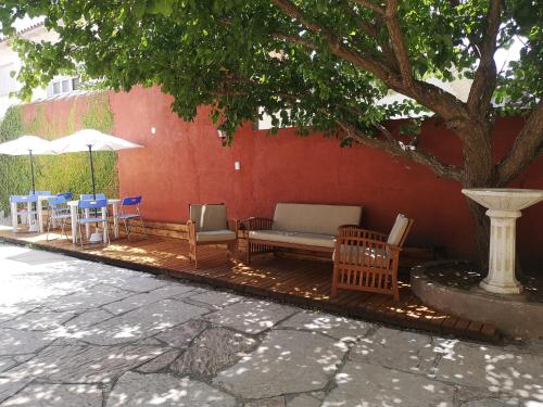 un patio con sillas y mesas y un árbol en los Apartamentos al-Andalus de Villa Gesell