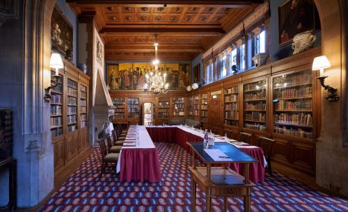 a large room with tables and chairs in a library at Schlosshotel Kronberg - Hotel Frankfurt in Kronberg im Taunus