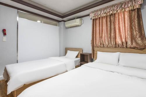 two beds in a room with a window at Keumkang Motel in Seoul