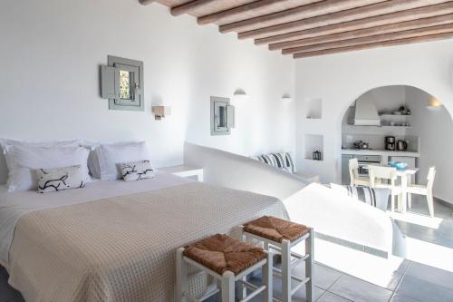 a white bedroom with a bed and two stools at Provalma in Áno Meriá