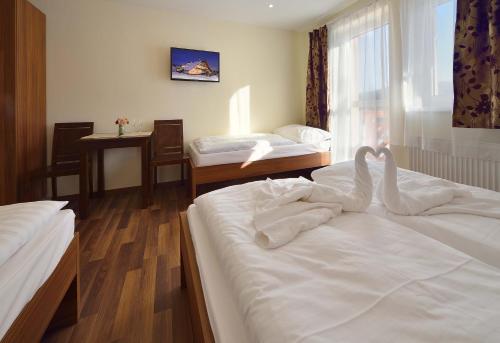 two swans sitting on two beds in a hotel room at Villa Gloria Rooms & Apartments in Donovaly