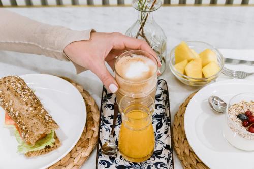 a person holding a glass of beer next to a table with food at Aparthotel Mariano Cubi Barcelona in Barcelona