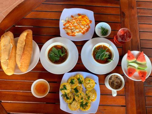 a table with plates of food on a wooden table at Sao Biển Cam Ranh - Starfish Cam Ranh in Cam Ranh