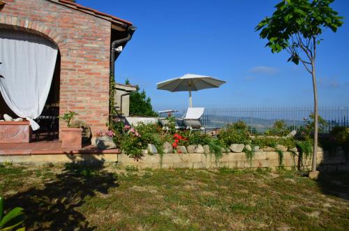 a brick house with an umbrella and a garden at Casa Magnolia in Terricciola