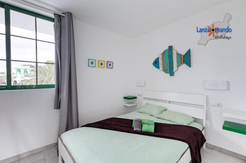 ein weißes Schlafzimmer mit einem Bett und einem Fenster in der Unterkunft Vivienda Vacacional Malu in Costa Teguise