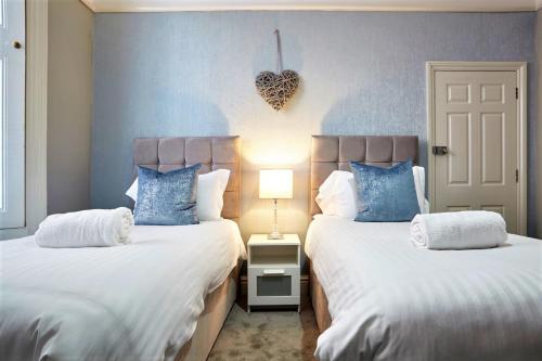 a bedroom with two beds with blue and white pillows at The Sunningdale - Your Apartment in Bristol
