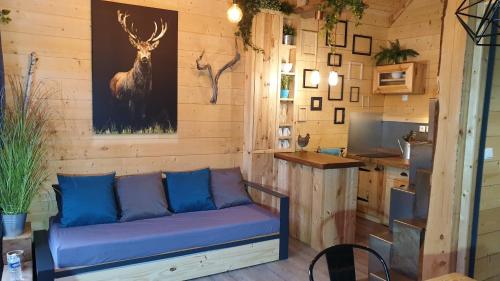 un canapé dans une pièce avec un tableau de cerfs sur le mur dans l'établissement Kabanéo - gîte et sauna- Samois sur Seine - Forêt de Fontainebleau, à Samois-sur-Seine