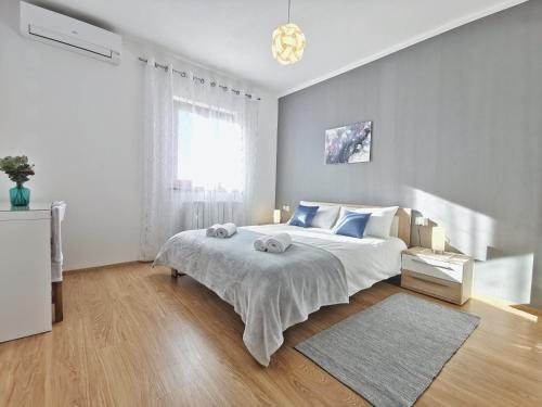 a white bedroom with a large bed and a window at Apartment Artemis in Višnjan
