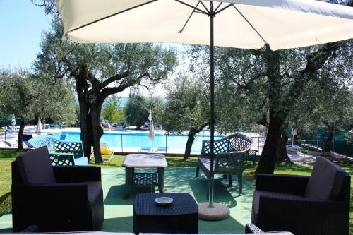 a patio with chairs and an umbrella and a pool at Villa Molino in Moniga