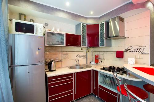 a kitchen with red cabinets and a stainless steel refrigerator at Люкс студия 1 комнатная,в центральном районе города in Mykolaiv
