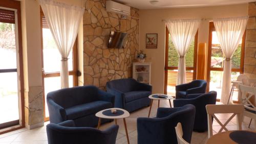 una sala de espera con sillas azules y una pared de piedra. en Toscana Lakeside Apartments I - II Family friend, en Siófok