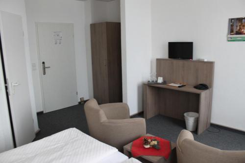 Zimmer mit 2 Stühlen und einem Schreibtisch mit einem TV in der Unterkunft Hotel Sächsischer Hof in Chemnitz