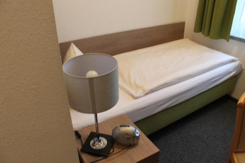 a bedroom with a bed and a lamp on a table at Hotel Sächsischer Hof in Chemnitz