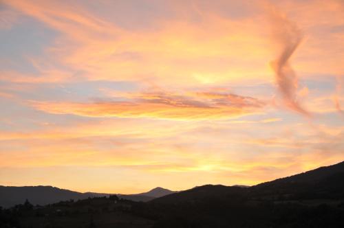 a cloudy sky at sunset with mountains in the background at Società Agricola Cacigolara in Borgo Val di Taro