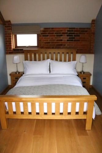 Blashford Manor Farmhouse - The Shetland Cottage في رينغوود: غرفة نوم بسرير خشبي كبير مع مصباحين