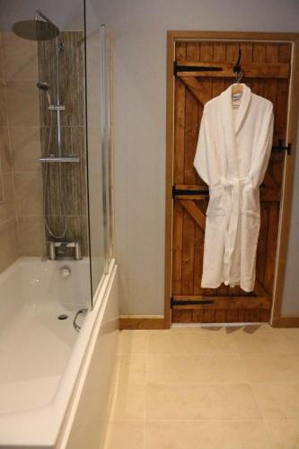 a bathroom with a shower and a white robe on a door at Blashford Manor Farmhouse - The Shetland Cottage in Ringwood